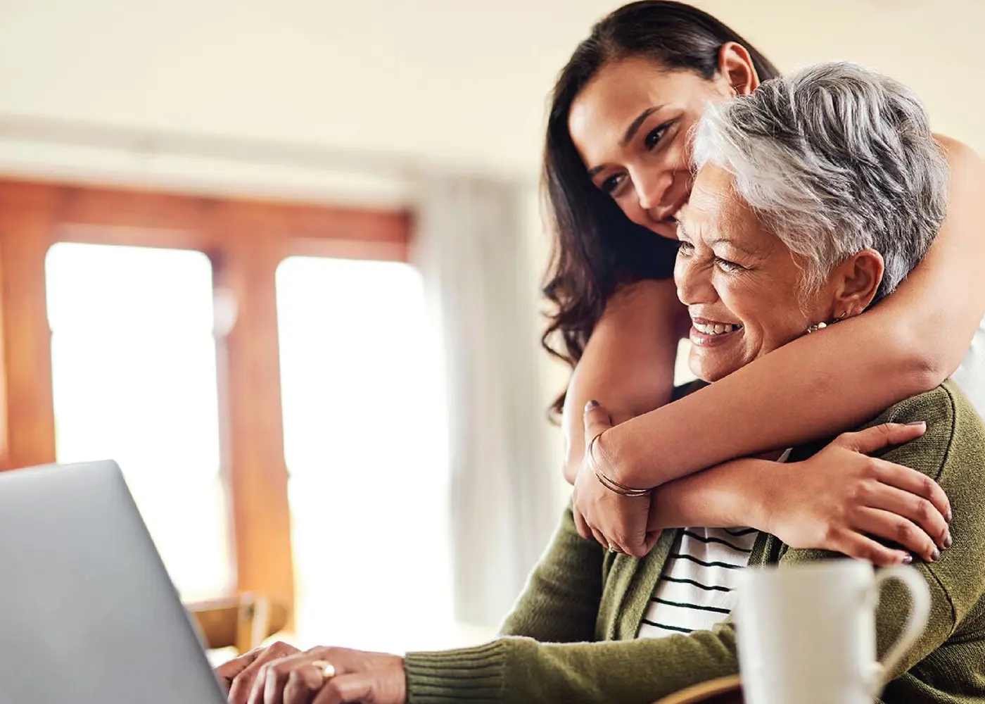 verdure-sciences-daughter-hugging-mother-working-on-laptop-1400x1000